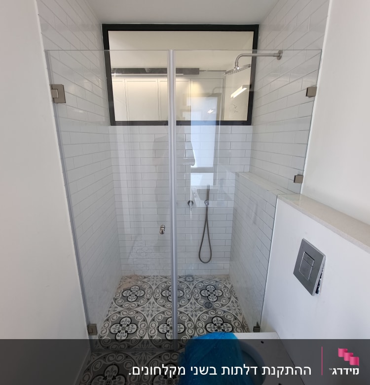 מקלחת עם דלת זכוכית, ראש מקלחת וקירות אריחים לבנים